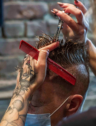 Alysha Osborne cutting hair with a red comb, and a pair of silver scissors. 